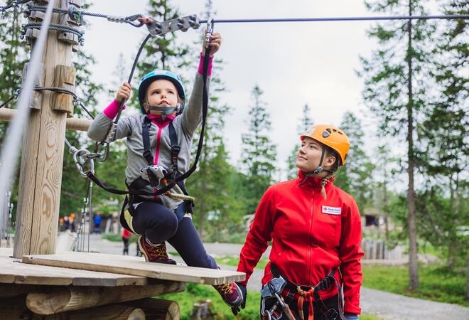 Barn i klatrepark får veiledning av voksen fra Røde kors